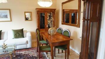 A dining area with a wooden table and chairs, a chandelier, a cabinet, and a mirror.