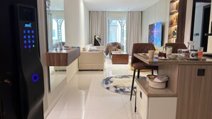 Un salon moderne avec un canapé, une table basse et un téléviseur. Il y a également un coin cuisine avec un comptoir et un réfrigérateur.