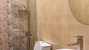 Een badkamer met douche, toilet en wastafel.
