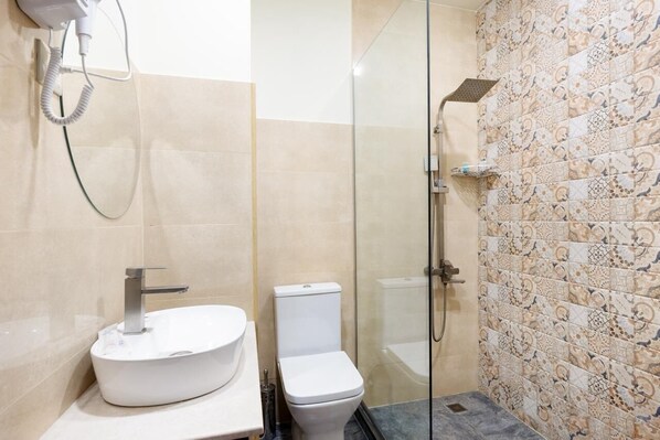 A bathroom with a white sink, toilet, and glass-enclosed shower area. - Hotel Melodia Kazbegi (Stepantsminda)