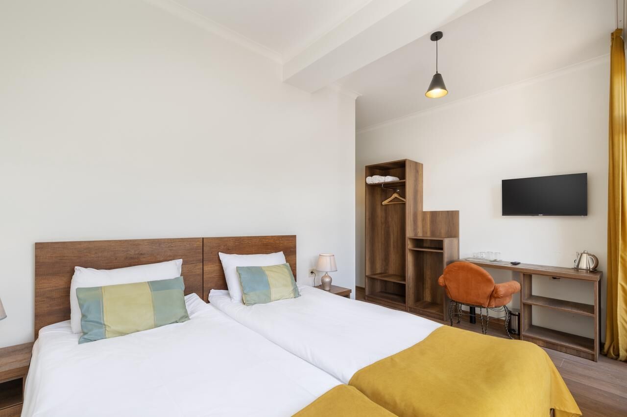 Habitación de hotel con dos camas, un escritorio, una silla, un televisor y un armario.