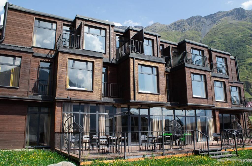 A multi-story building with balconies, large windows, and outdoor seating.
