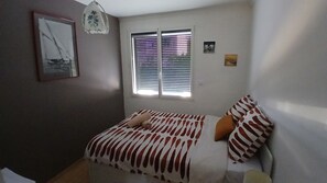 A bedroom with a bed, a window with blinds, a wall-mounted lamp, and a framed picture. - VILLA DU SUD (Boujan-sur-Libron)