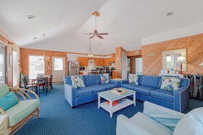 A cozy living room with a blue sofa set, a dining area, and a kitchen in the background. - JL #656 | Terrill Cottage | Semi-Oceanfront | Horizon Ocean View (Kitty Hawk)