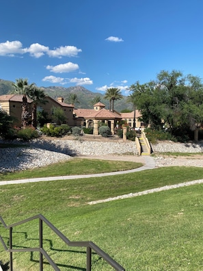 A resort with a paved walkway, palm trees, and a mountain backdrop. - Spacious 3-bedroom condo near beautiful Sabino Canyon with AC pool, spa and gym. (Tucson)