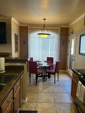 A kitchen with a dining table, chairs, a chandelier, and a window with curtains. - Spacious 3-bedroom condo near beautiful Sabino Canyon with AC pool, spa and gym. (Tucson)
