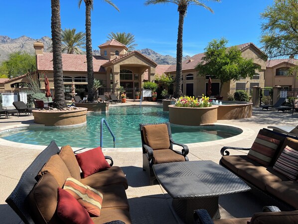 A pool area with lounge chairs and a hot tub, surrounded by palm trees and a mountain backdrop. - Spacious 3-bedroom condo near beautiful Sabino Canyon with AC pool, spa and gym. (Tucson)