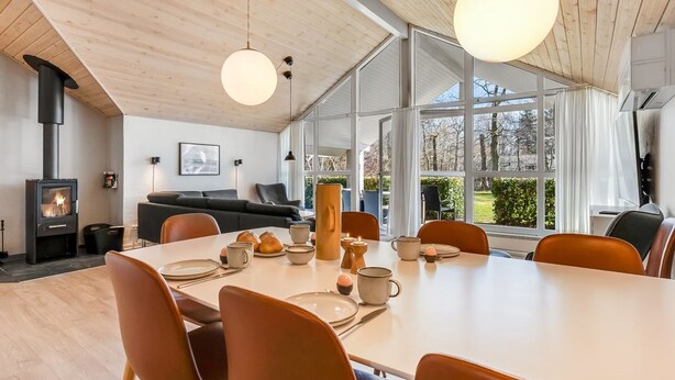 Ein modernes Interieur mit Essbereich, Kamin und großen Fenstern.