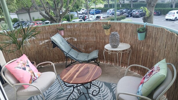 A covered outdoor seating area with wicker furniture, a round table, and potted plants. - Charming T2 near Avignon festival (Montfavet)