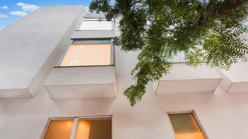 A building with multiple windows, a tree in the foreground, and a clear sky.