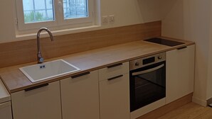 A kitchen with a sink, dishwasher, oven, and a window with a view of buildings.