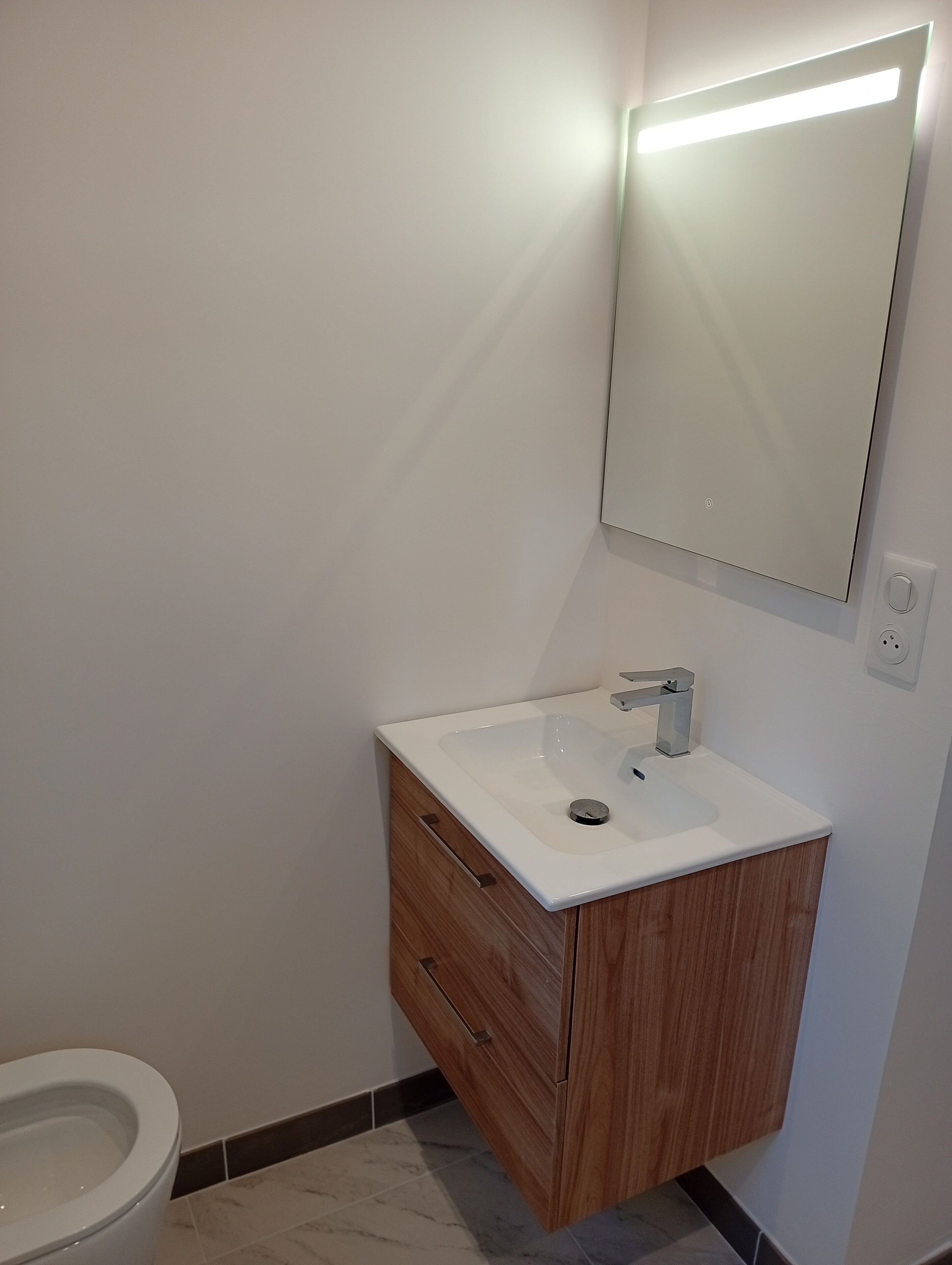 Ein Badezimmer mit Waschbecken, Holzschrank und Spiegel.