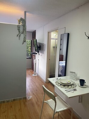 A compact room with a dining table, a chair, a mirror, and a plant. - Cozy studio apartment in the Eucharistic Quarter. (Cali)
