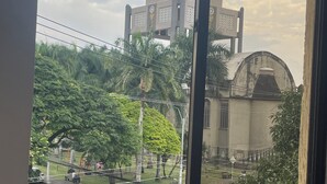 Une vue d’une église surmontée d’une croix, entourée de verdure et bordée par une rue.