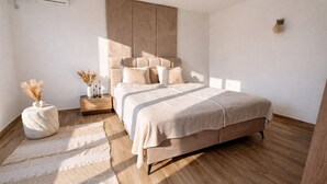 Un dormitorio con cama, mesitas de noche, aire acondicionado de pared y suelo de madera.