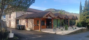 A reception area with a sign, a wooden building, and a mountain backdrop. - Villa at Domaine de l'Espinet - Quillan 11500 (Quillan)
