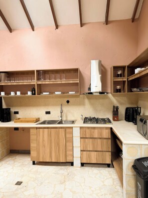 A kitchen with a stone floor, wooden cabinets, a sink, a stove, and a microwave. - ! House in Santa Fe de Antioquia Patio Colonial Boutique (Santa Fé de Antioquia)