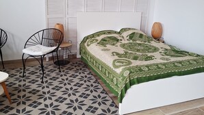A bedroom with a bed, a chair, a small table, and a decorative wall panel. - La Grange de Marie studio 2 persons (Monampteuil)