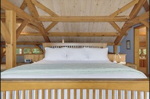 Ein Zimmer mit Holzrahmen, einem Bett, einem Nachttisch und einem Fenster.
