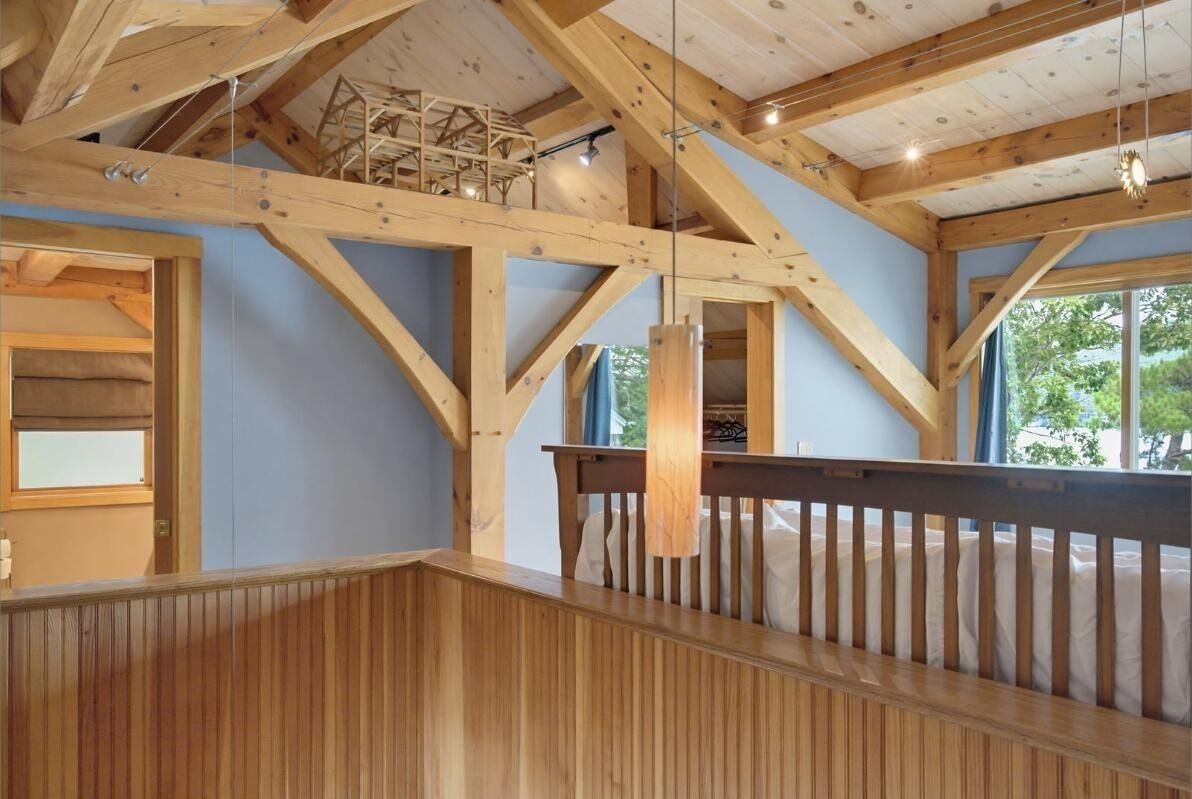 Una habitación con vigas de madera a la vista, un banco de madera y una ventana con vistas al verdor.