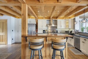A modern kitchen with a central island, bar stools, and wooden beams on the ceiling. - Lakefront Sandy Beach Private Dock Fire Pit Views Peaceful (Alton)