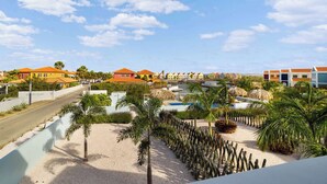 Een resort met kleurrijke gebouwen, een zwembad en een cactustuin.