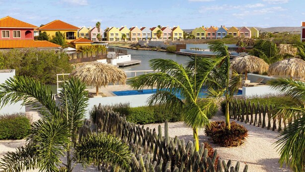 Een resort met kleurrijke gebouwen, een zwembad en een rivier.