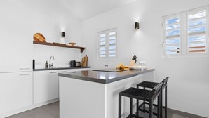 Een moderne keuken met witte kasten, een centraal eiland en een barkruk.