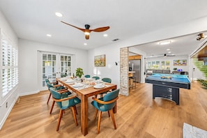 A spacious dining area with a wooden table and teal chairs, a kitchen with a refrigerator, and a pool table. - 6 King Suites | Pool + Game Room Oasis Near Beaches (Seminole)