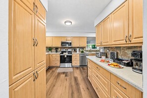 A modern kitchen with wooden cabinets, stainless steel appliances, and a coffee bar. - 6 King Suites | Pool + Game Room Oasis Near Beaches (Seminole)