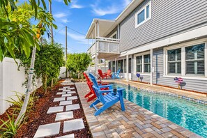 A swimming pool area with a covered deck, red and blue lounge chairs, and a pathway leading to the pool. - 6 King Suites | Pool + Game Room Oasis Near Beaches (Seminole)