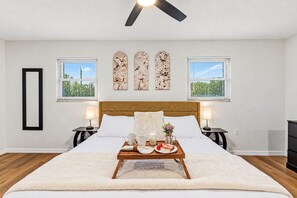 A bedroom with a bed, bedside lamps, a tray with breakfast items, and artwork on the wall. - 6 King Suites | Pool + Game Room Oasis Near Beaches (Seminole)