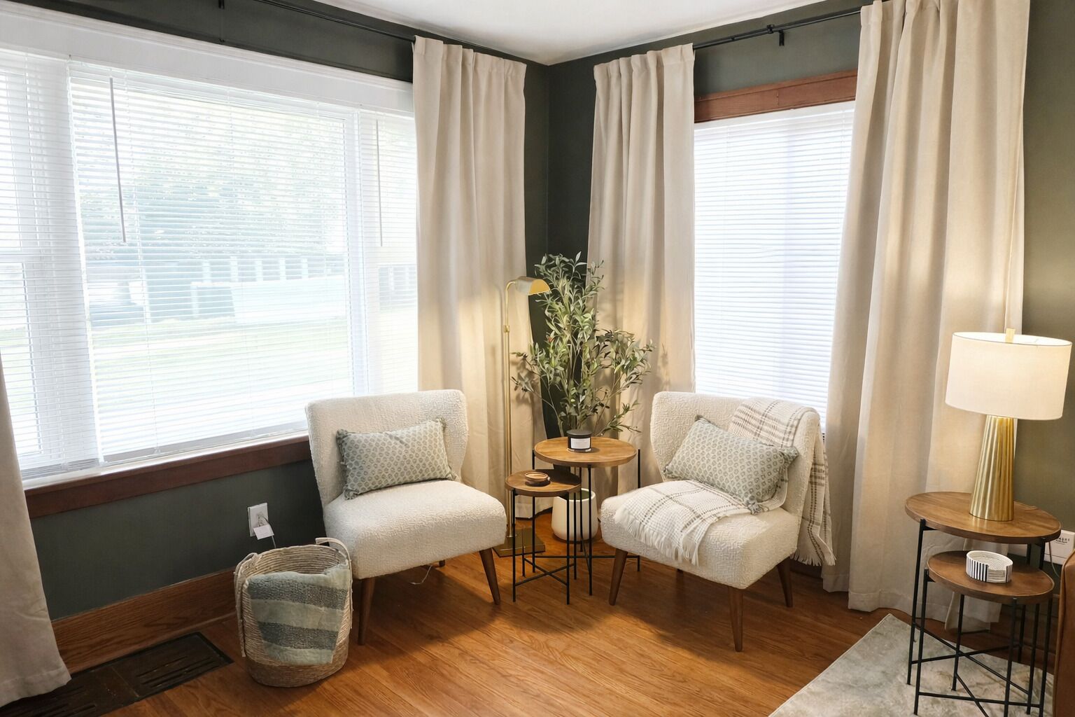 Une pièce avec deux fauteuils, une petite table sur laquelle est posée une plante, une lampe et une vue dégagée grâce à de grandes fenêtres.