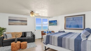 A modern bedroom with a bed, a sofa, a desk, and a view of the sea. - The Vista: Oceanfront studio~View~King bed~Pool~Gym (Daytona Beach)