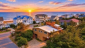 Ett bostadsområde vid kusten med hus, ett stoppskylt och en fri utsikt över havet vid solnedgången.