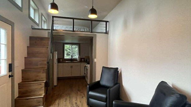 Un interior modern amb una escala, mobles de pell negra i il·luminació penjant.
