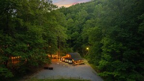 A lodge with a gravel driveway, surrounded by dense forest.