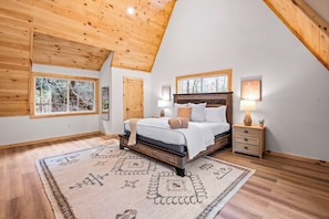 A bedroom with a wooden ceiling, a bed with a headboard, a nightstand, a window, and a rug. - Creekside Lodge on 6 Acres | Game Room, 8-Person Hot Tub, Sleeps 17 (Sevierville)