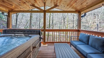 Une terrasse en bois avec un jacuzzi, un canapé et une table.