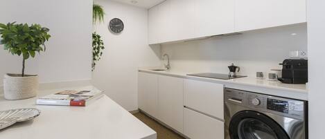 Una cocina moderna con lavadora integrada, un lavabo y un reloj en la pared.
