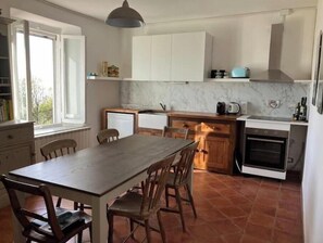 A kitchen with a dining table and chairs, a stove, a microwave, and a window.