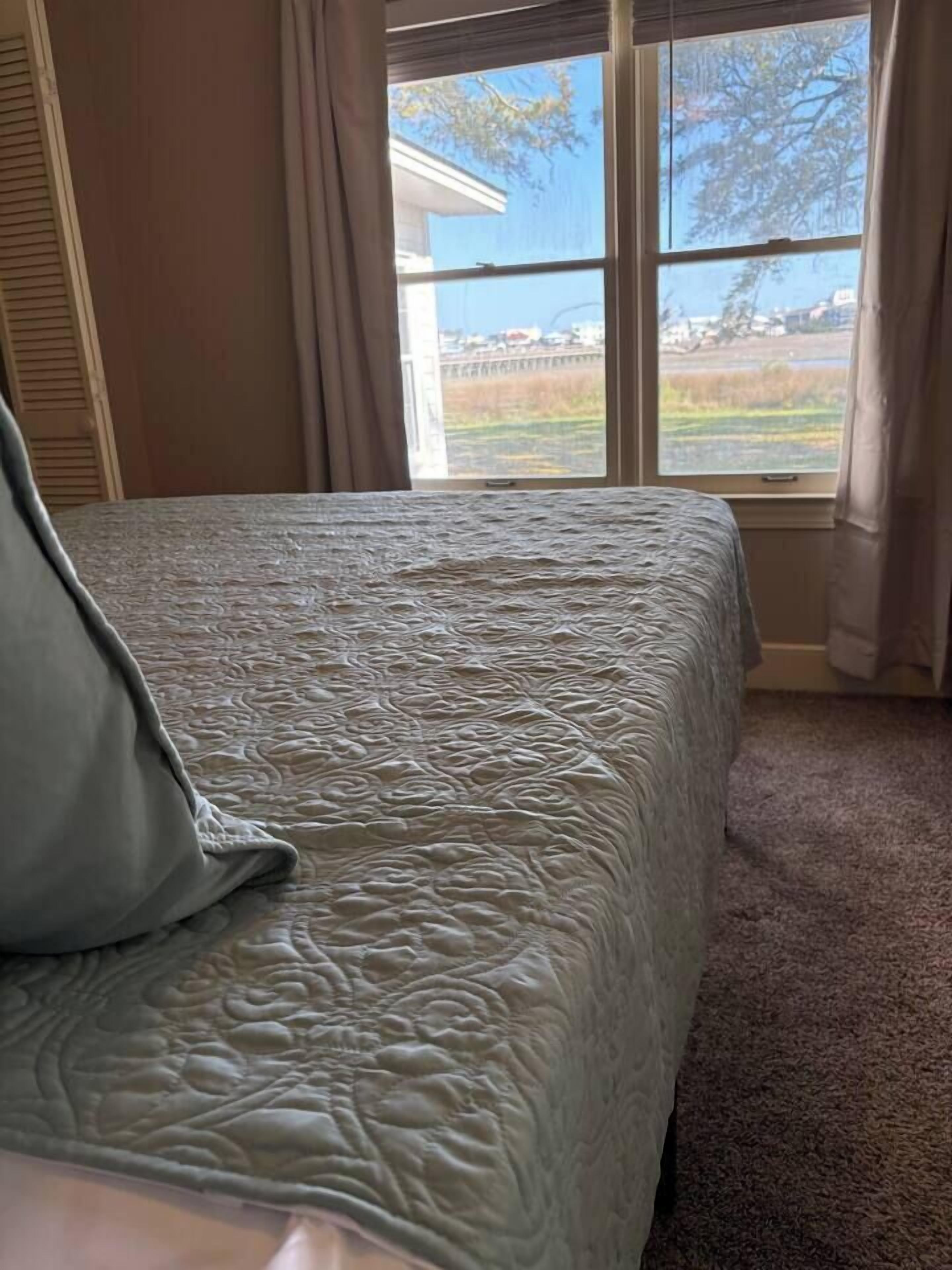 Een slaapkamer met een bed, een raam en uitzicht op de omgeving.