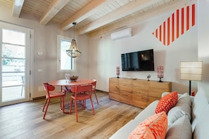 Une pièce avec un plafond en bois, une table à manger avec des chaises, un canapé, un téléviseur et un meuble.