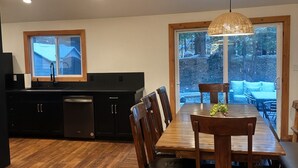 A modern kitchen with dark cabinetry, a wooden dining table, and a large window with a view of a snowy landscape. - Spacious 6-bedroom house in McCall - walkable to Payette Lake, Shore Lodge (McCall)