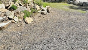 A cabin with a gravel driveway, surrounded by trees and a stone wall. - Spacious 6-bedroom house in McCall - walkable to Payette Lake, Shore Lodge (McCall)