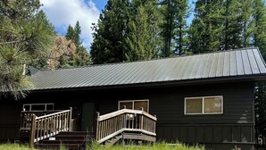 A cabin with a metal roof, wooden deck, and stone steps leading to a wooden door. - Spacious 6-bedroom house in McCall - walkable to Payette Lake, Shore Lodge (McCall)