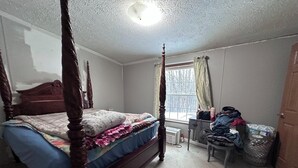 Un dormitorio con cama con dosel, un escritorio con silla y un ventanal con cortinas.