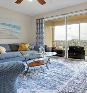 A living room with a sofa, a glass coffee table, and a patterned rug. - Disney Fun in the Sun! 4th Floor Sunset Retreat! Kissimmee, FL (Kissimmee)