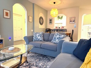 Ein Wohnzimmer mit einer Couch, einem Glastisch und einem gemusterten Teppich.