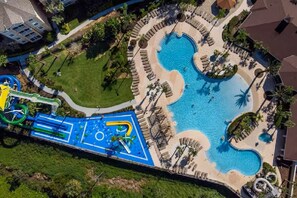 An aerial view of a resort with a large swimming pool, a water slide, and lounge areas. - Disney Fun in the Sun! 4th Floor Relaxation Retreat! (Kissimmee)